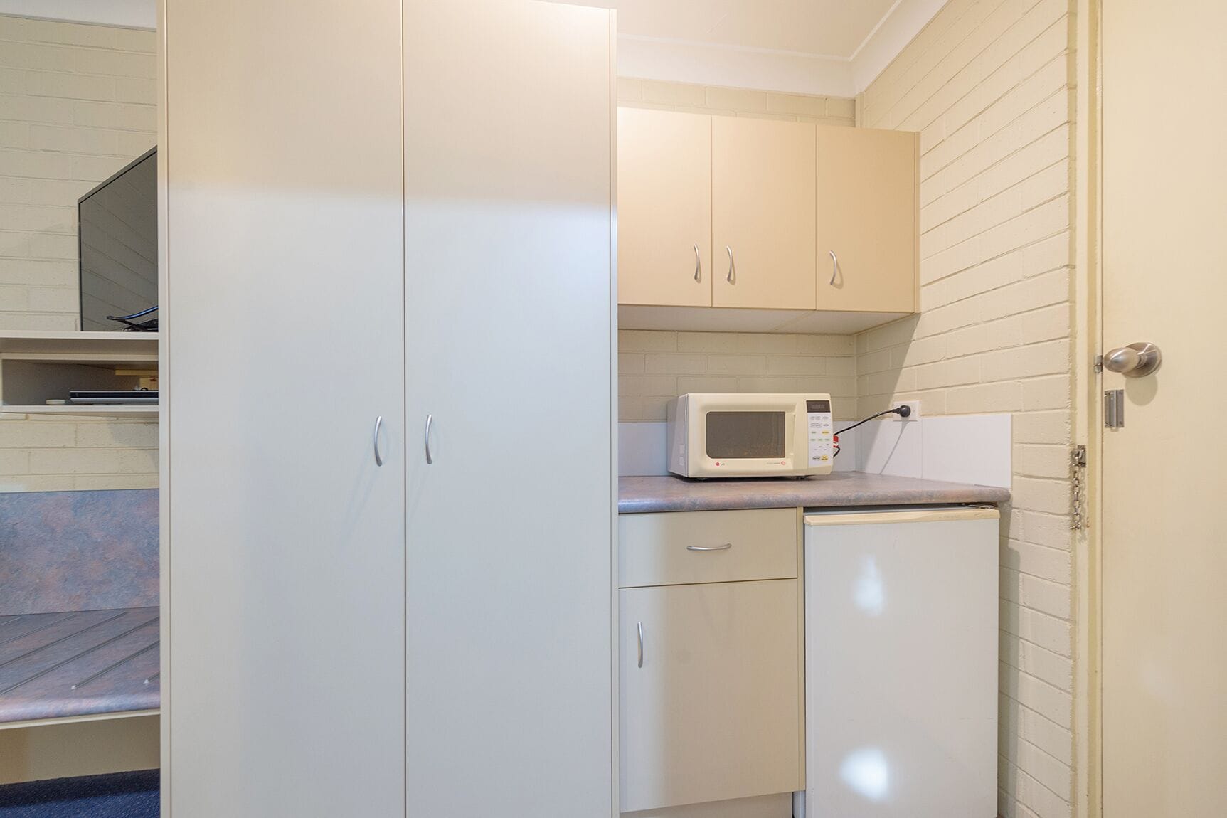 A compact kitchen with white cabinets, a microwave, and a small countertop.
