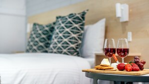 A neatly made bed with white linens, a wooden headboard, and a nightstand with a glass of red wine and a plate of snacks. - Fitzroy Motor Inn Grafton (Grafton)