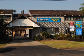 Un motor inn Fitzroy con un cartel, un área de estacionamiento y la entrada del edificio.