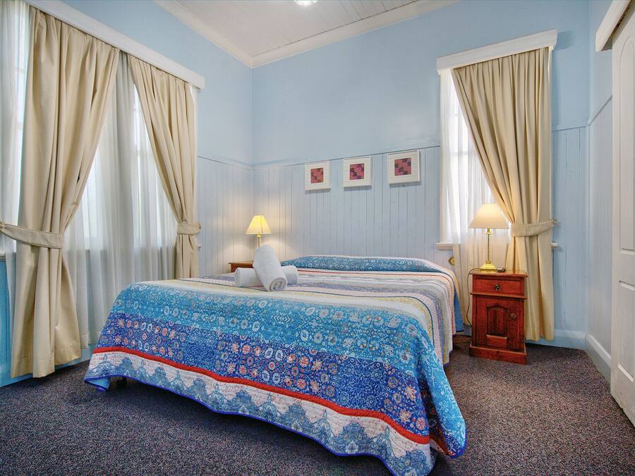A bedroom with a double bed, two bedside tables with lamps, and a wall with three framed pictures.