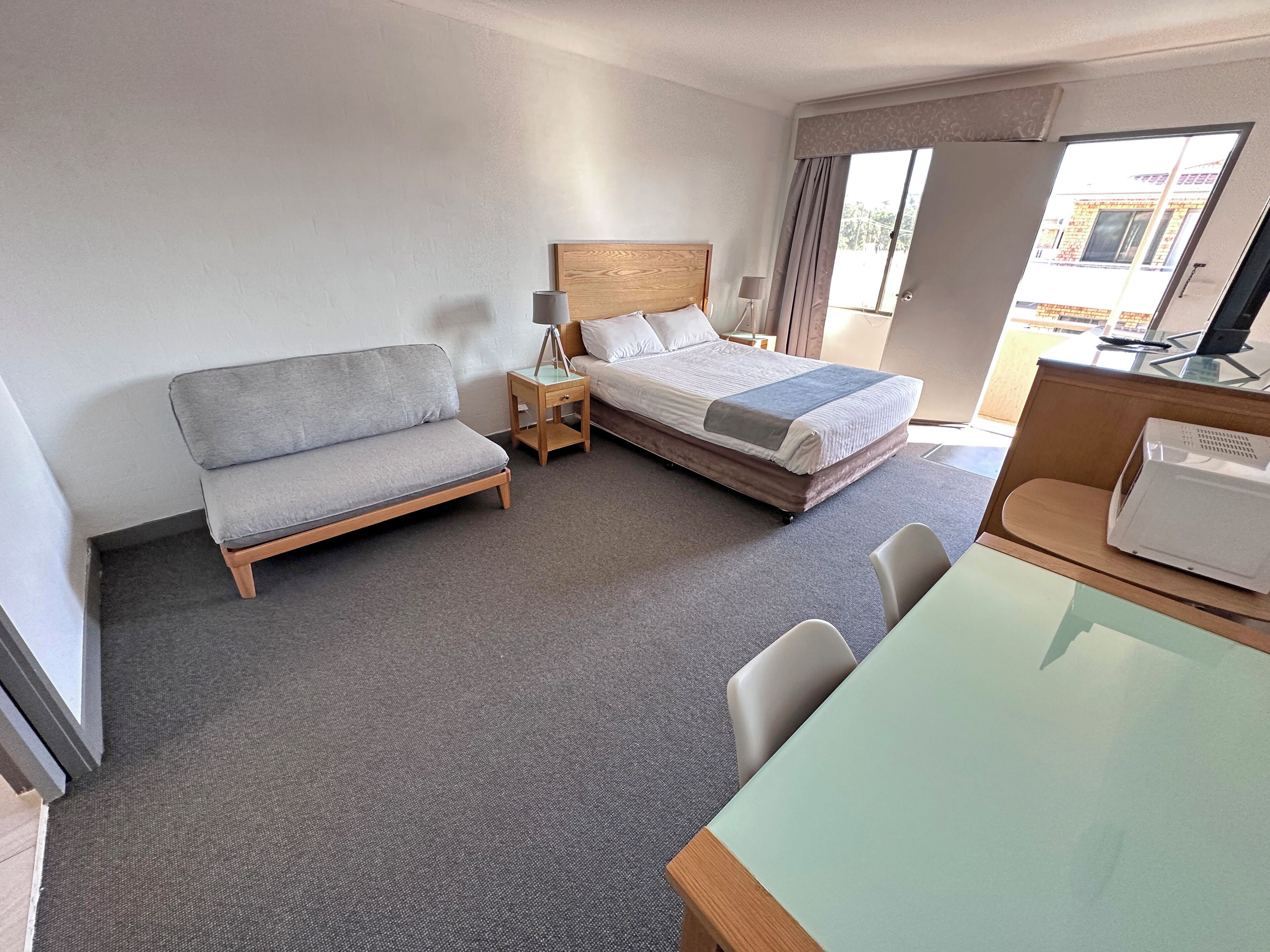 A hotel room with a bed, a sofa, a desk, and a chair.