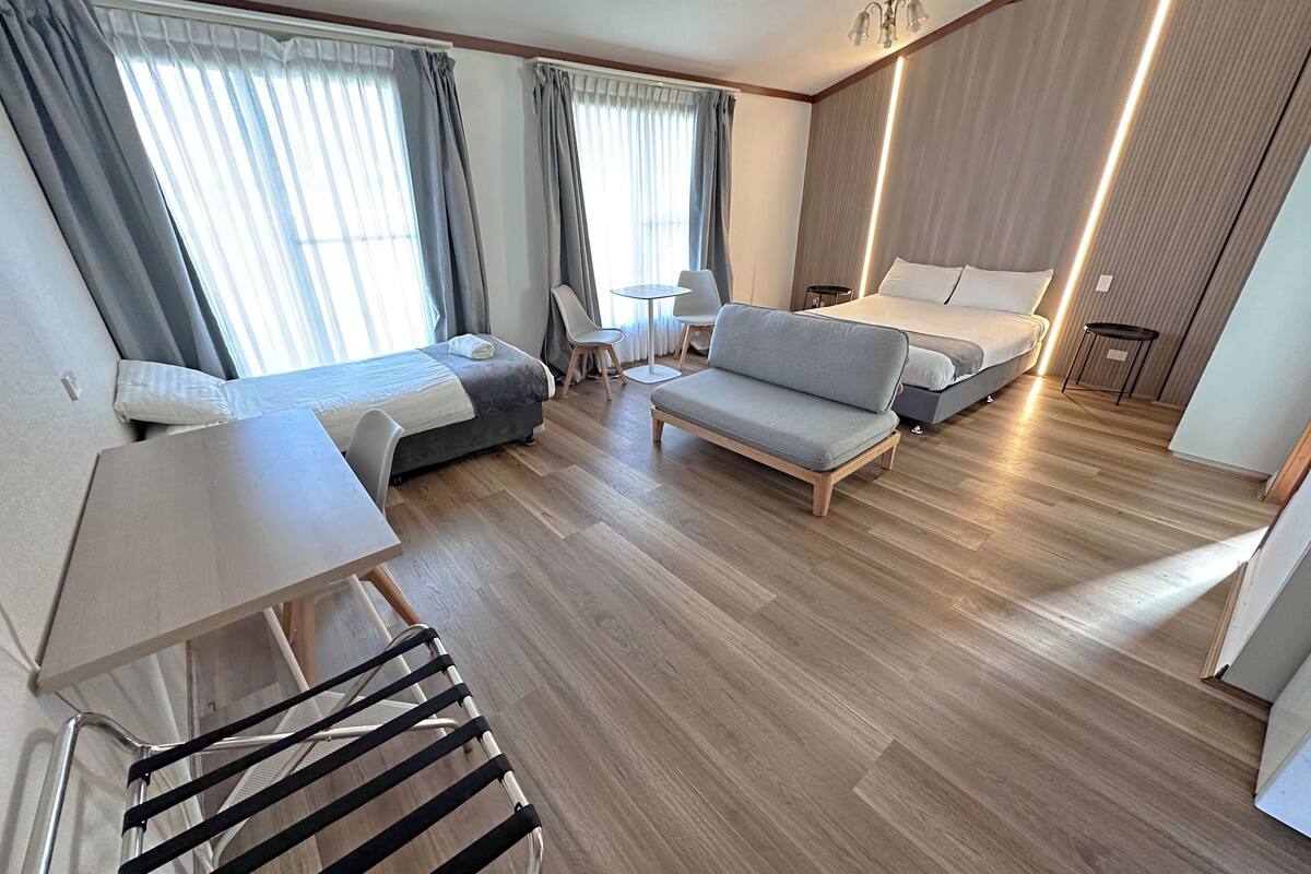A modern hotel room with a bed, sofa, and a small table.