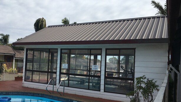 A building with large windows and a swimming pool in front. - Town & Country Motel (Strathfield)