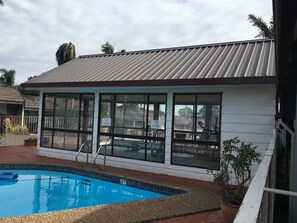 A building with large windows and a swimming pool in front. - Town & Country Motel (Strathfield)