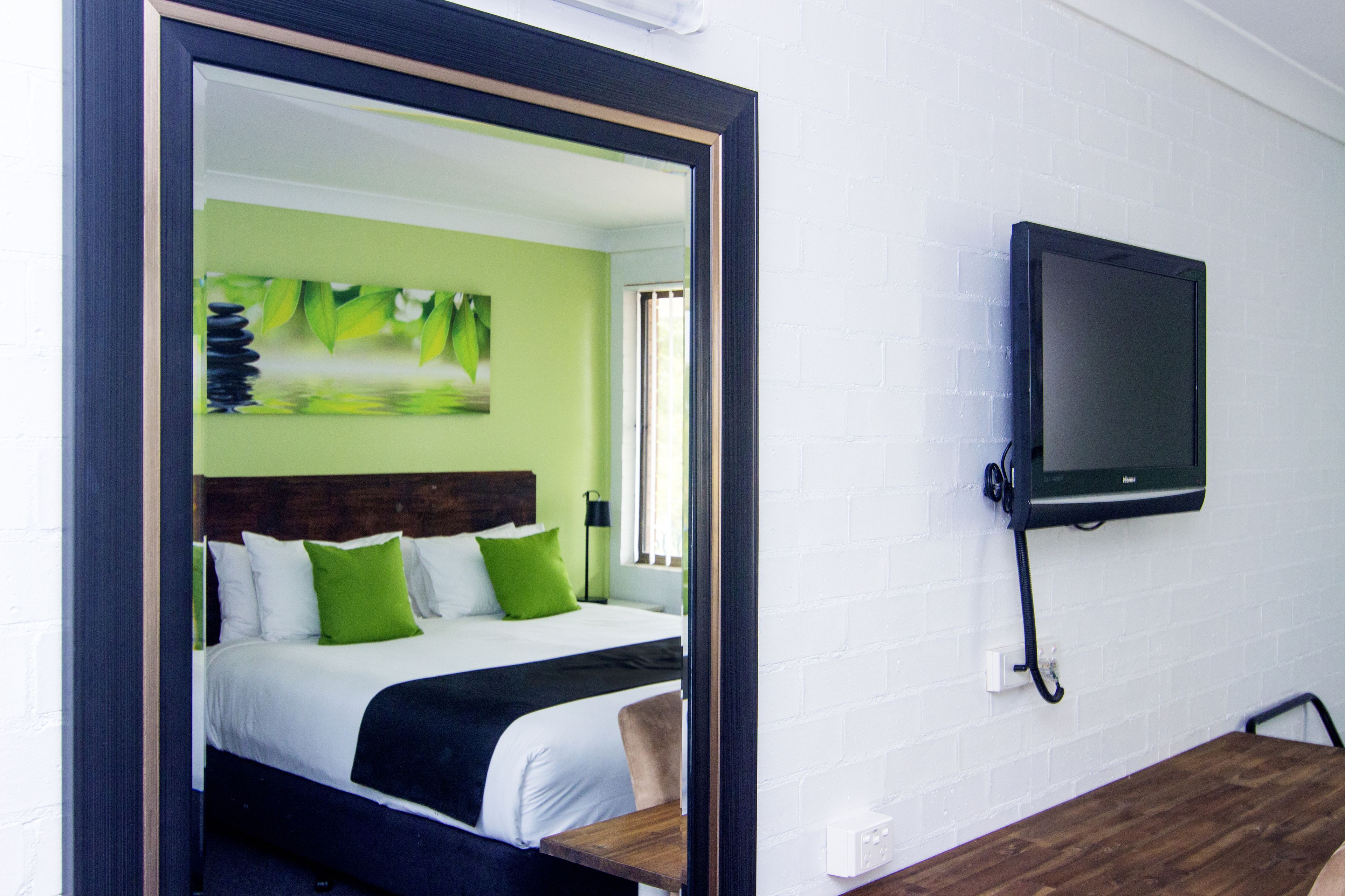 A hotel room with a bed, a TV mounted on the wall, and a wooden table.