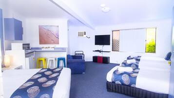 A hotel room with two beds, a desk, a chair, a TV, and a painting on the wall.