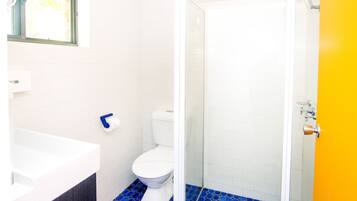 A bathroom with a white toilet, a white bathtub, and a glass-enclosed shower.