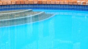A clear blue swimming pool with a tiled edge and a brick border. - Crescent Motel (Taree)