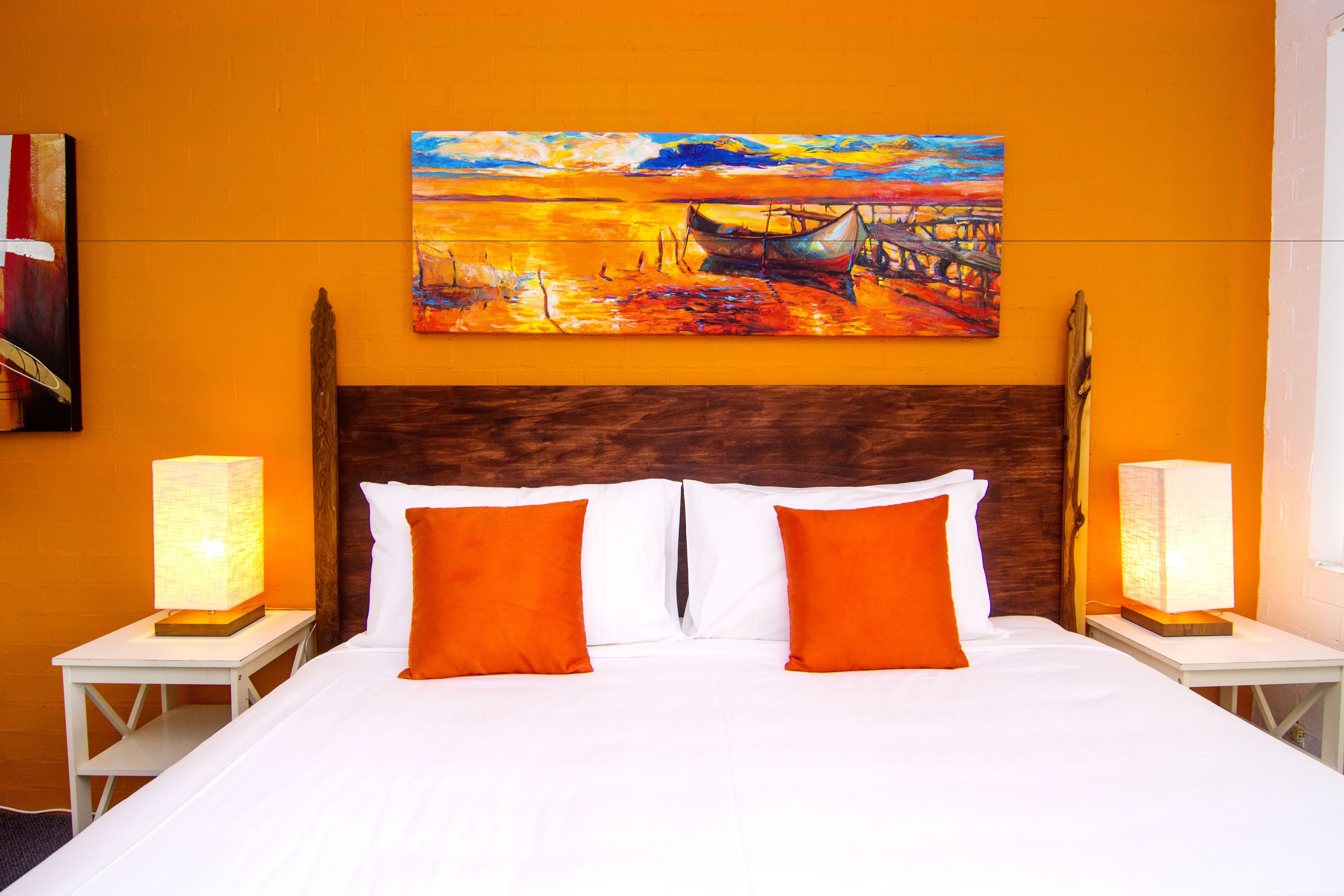 A hotel room with a large bed, two nightstands, two lamps, and a painting on the wall.