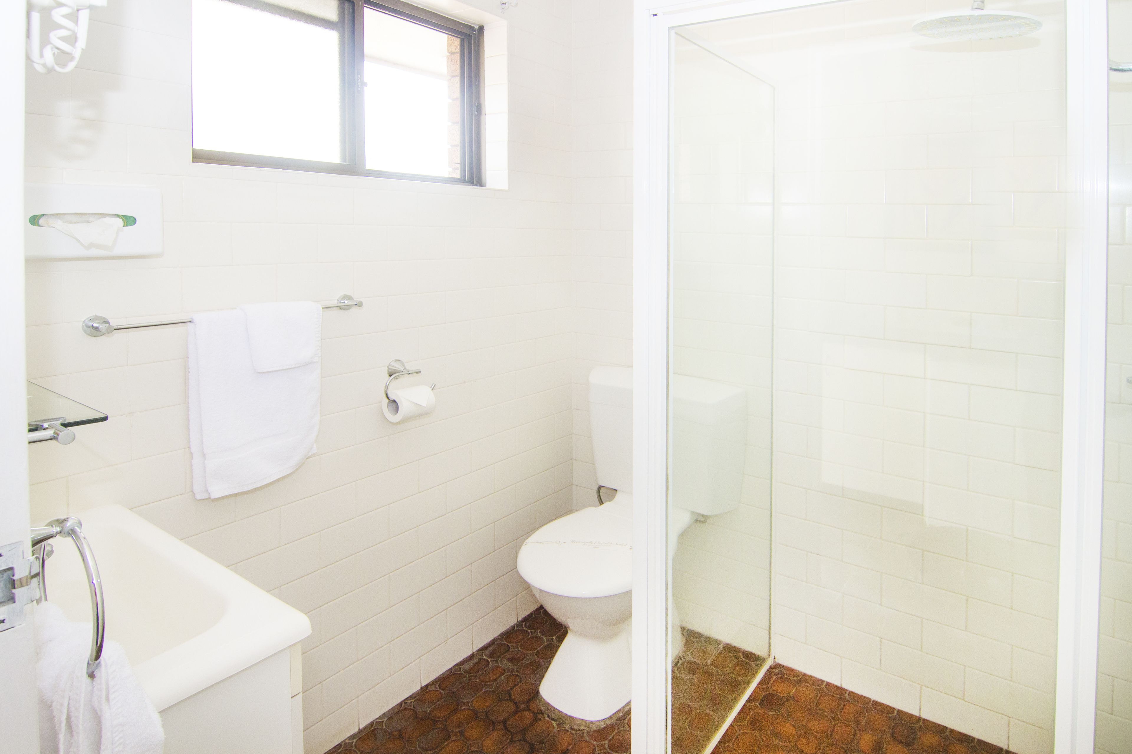 Un baño con bañera blanca, inodoro y zona de ducha.