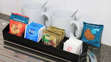 En bakke med kaffeposer, teposer og småkager.