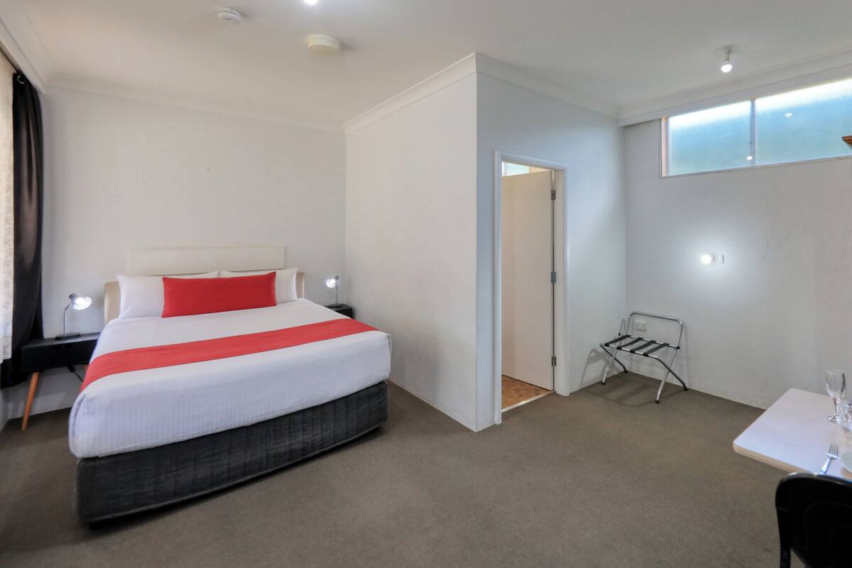 Una habitación de hotel con cama, una pequeña mesa para comer, una silla y un armario.