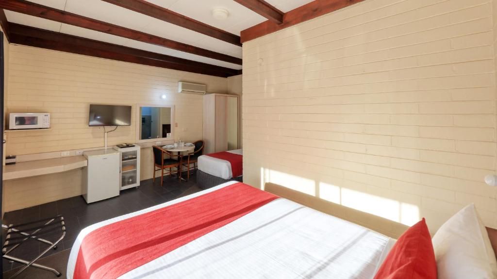 A hotel room with a bed, a desk, a chair, a TV, and a wardrobe.