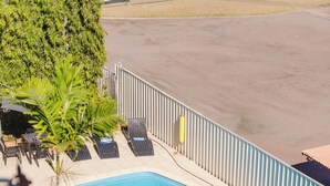 A swimming pool with lounge chairs and palm trees. - The Heritage Darwin (Darwin)