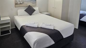 A hotel room with a bed, a nightstand, a wardrobe, and a painting on the wall.