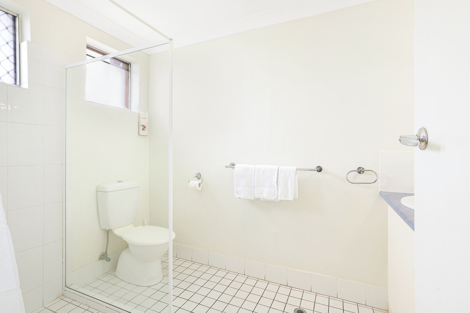 A bathroom with a toilet, a glass shower enclosure, and a towel rack.