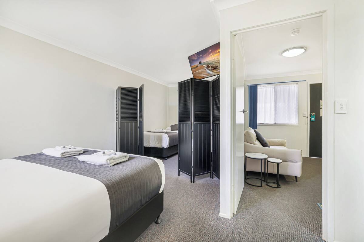 Una habitación de hotel con cama, escritorio, silla y armario.