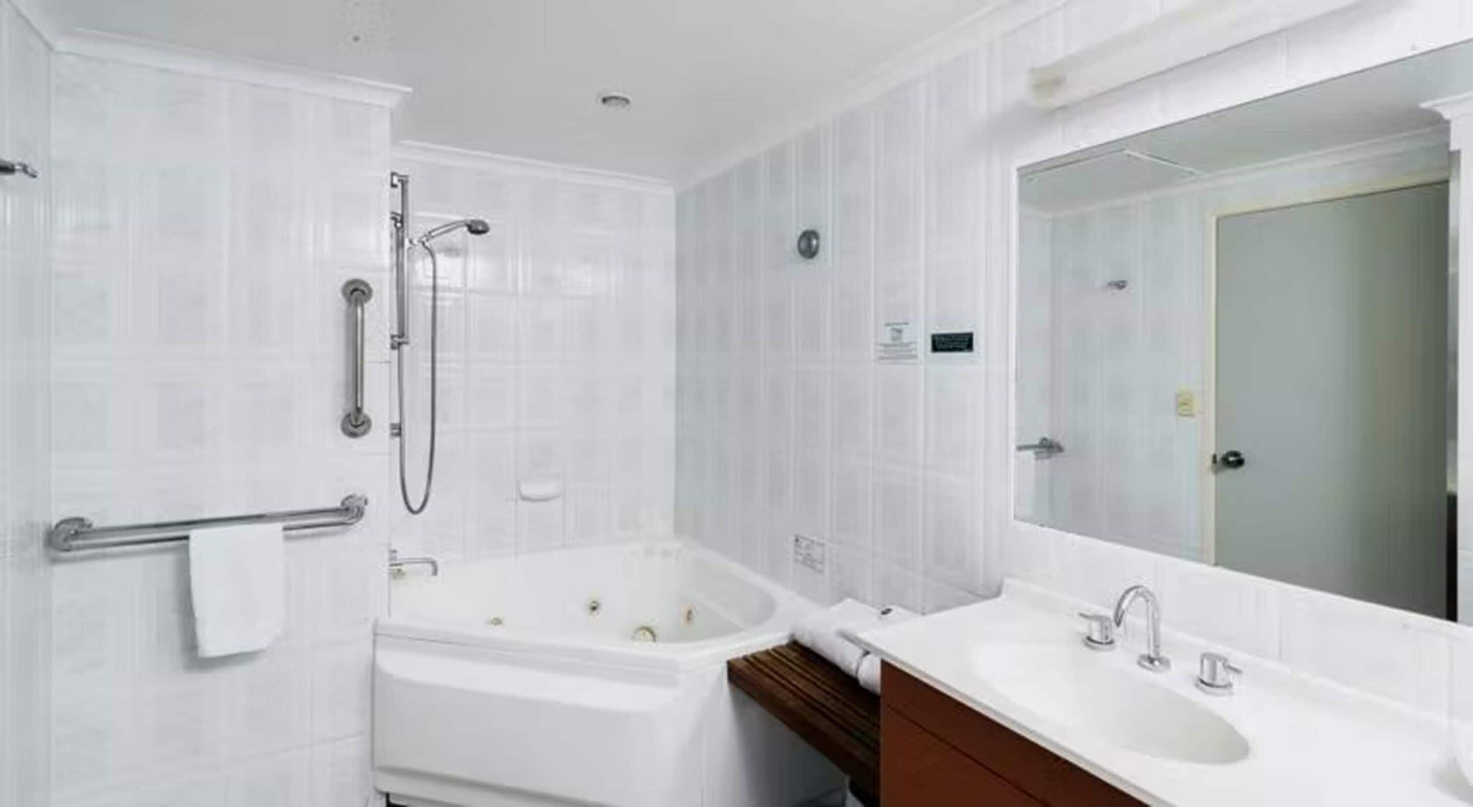 A modern bathroom with a bathtub, a sink, and a large mirror.