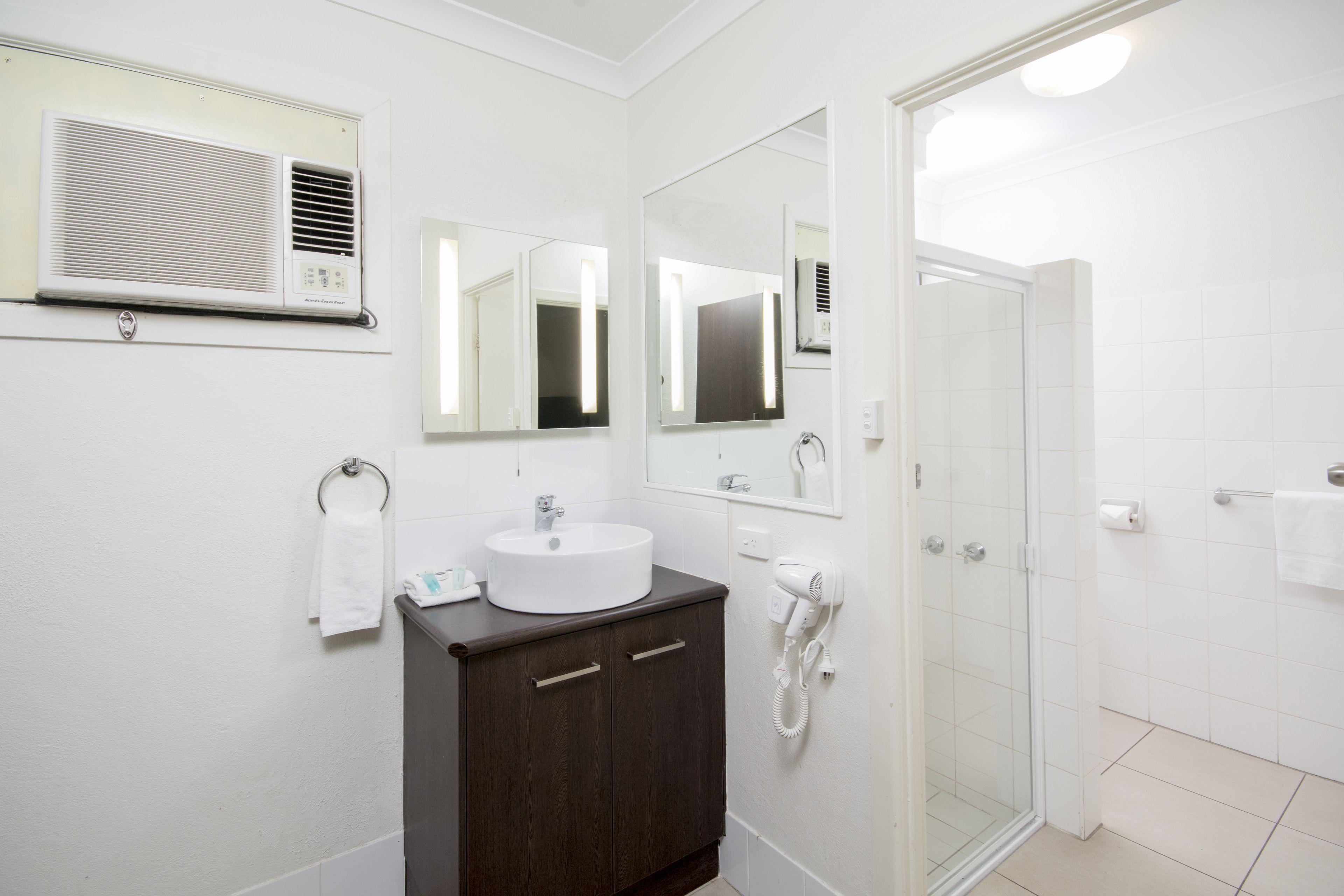 A modern bathroom with a sink, mirror, vanity, and a glass shower enclosure.