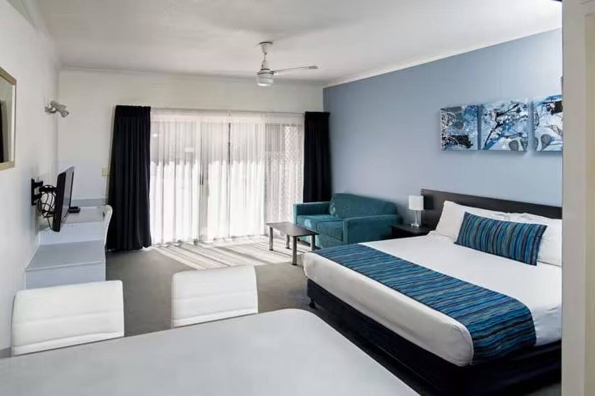 Una habitación de hotel con cama, escritorio, silla, televisor y baño.