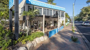 Un motel frente a la playa con asientos al aire libre y un patio cubierto.