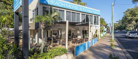 Un motel frente a la playa con asientos al aire libre y un patio cubierto.