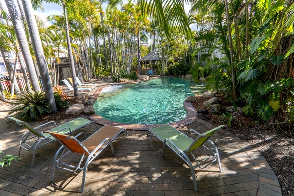 Una piscina al aire libre, sillones reclinables de piscina