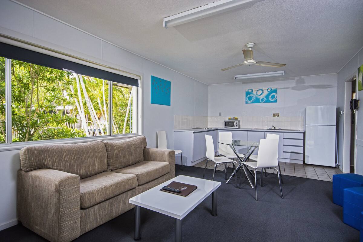 Un espacio habitable compacto con sofá, mesa de comedor y kitchenette.