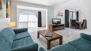 Una sala de estar con sofá, mesa de centro, televisor y comedor con sillas y una mesa.