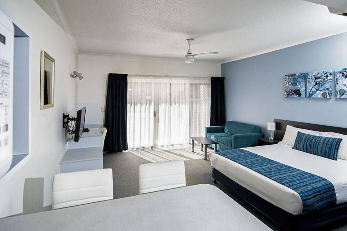 Habitación de hotel con una cama grande, un sofá, un escritorio y un balcón con cortinas.