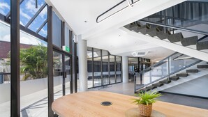 A modern interior with a wooden reception desk, a staircase, and large windows. - Mercure Rockhampton (Rockhampton)