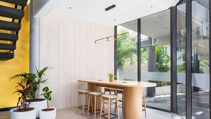 A modern interior with a round wooden table, four bar stools, and three potted plants. - Mercure Rockhampton (Rockhampton)