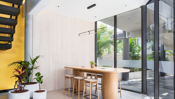 A modern interior with a round wooden table, four bar stools, and three potted plants. - Mercure Rockhampton (Rockhampton)
