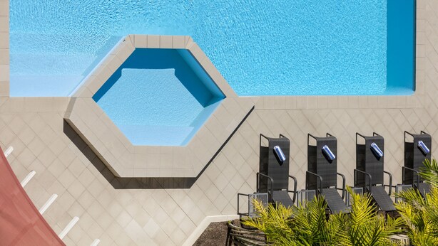A swimming pool with a hexagonal section, lounge chairs, and a tiled deck. - Mercure Rockhampton (Rockhampton)