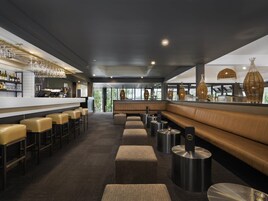 Un área de bar moderna con asientos de cuero, una barra y vistas al exterior.