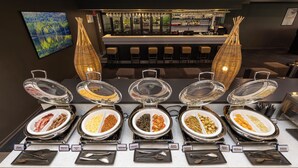 Un buffet avec des présentoirs indiquant les différents types de plats, un bar et un espace détente avec des chaises.