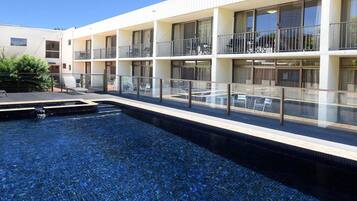 Una piscina al aire libre, sillones reclinables de piscina