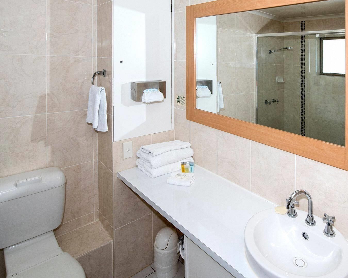 Un bagno con il water, un lavandino, uno specchio e una doccia.