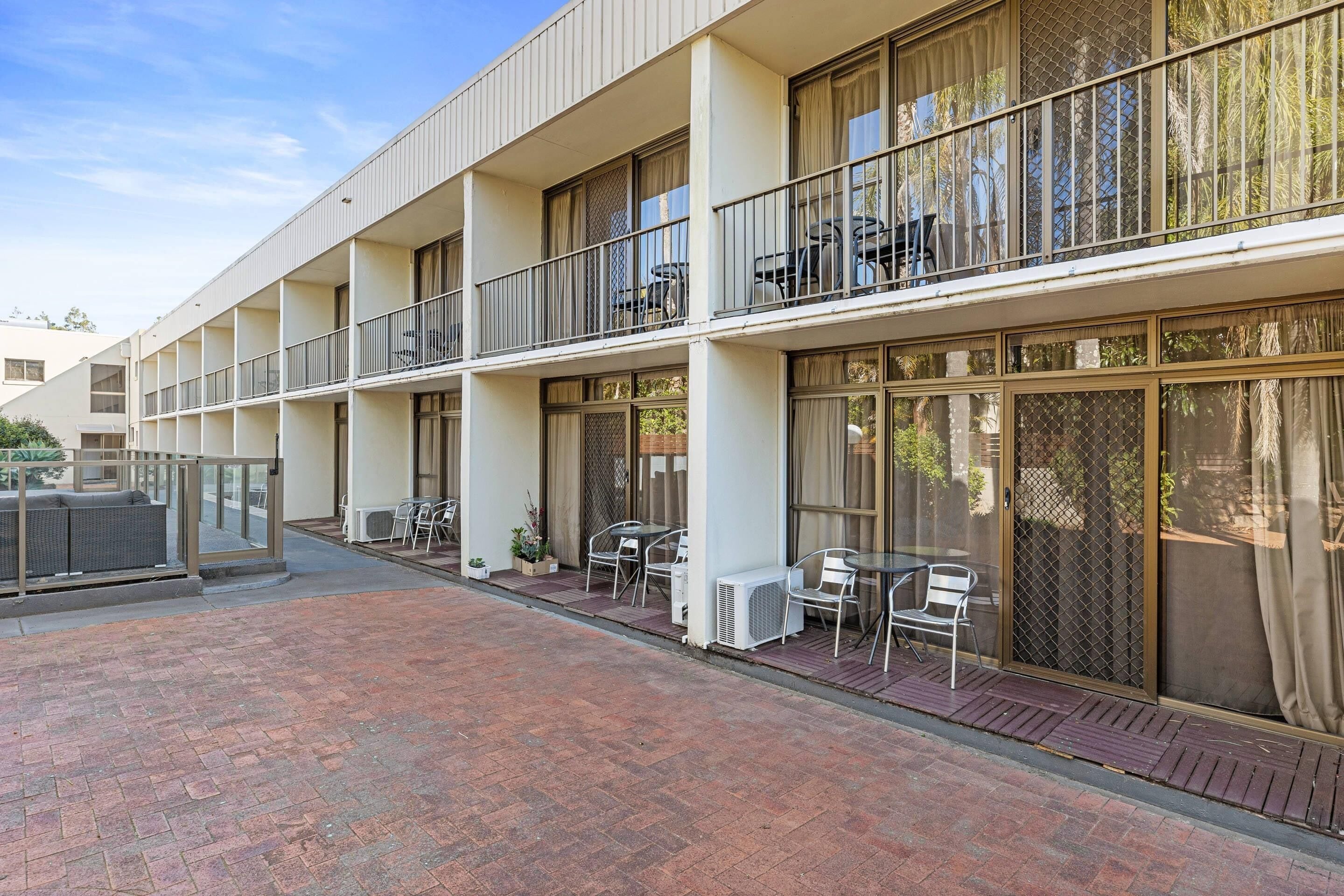 A multi-story hotel with balconies, outdoor seating, and large windows.