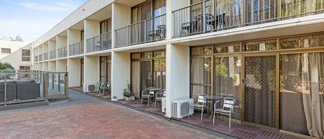 A multi-story hotel with balconies, outdoor seating, and large windows.