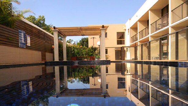 A modern building with a pool area, wooden pergola, and glass balconies. - Comfort Inn Grammar View (East Toowoomba)
