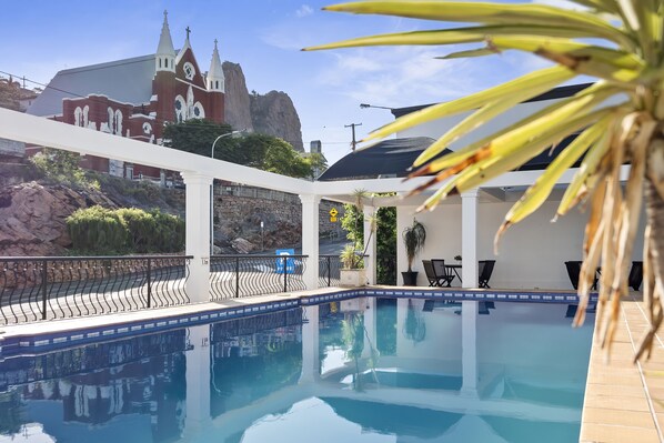 A swimming pool with a view of a church and rocky landscape.