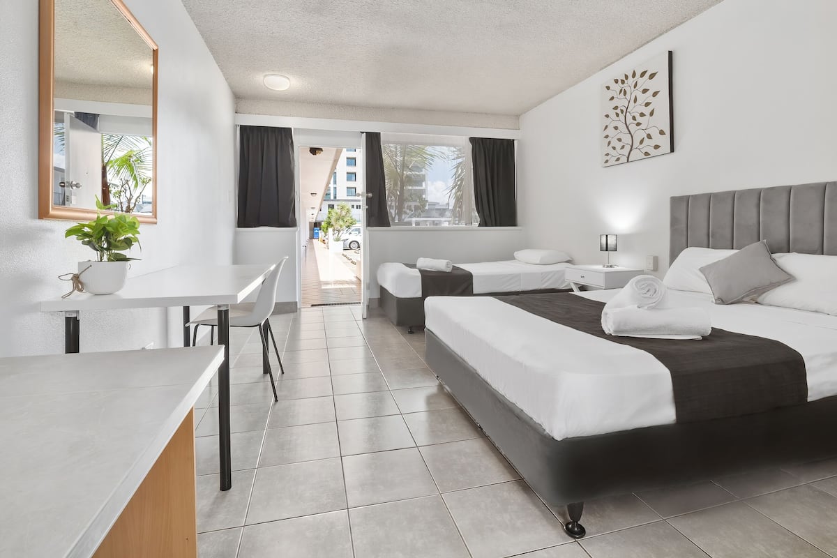 A modern hotel room with a bed, bedside table, and a desk with a chair.