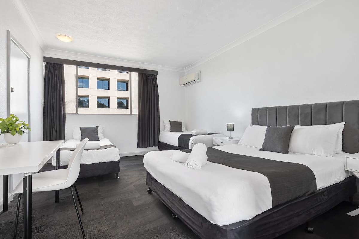 A hotel room with two beds, a desk, and a chair.