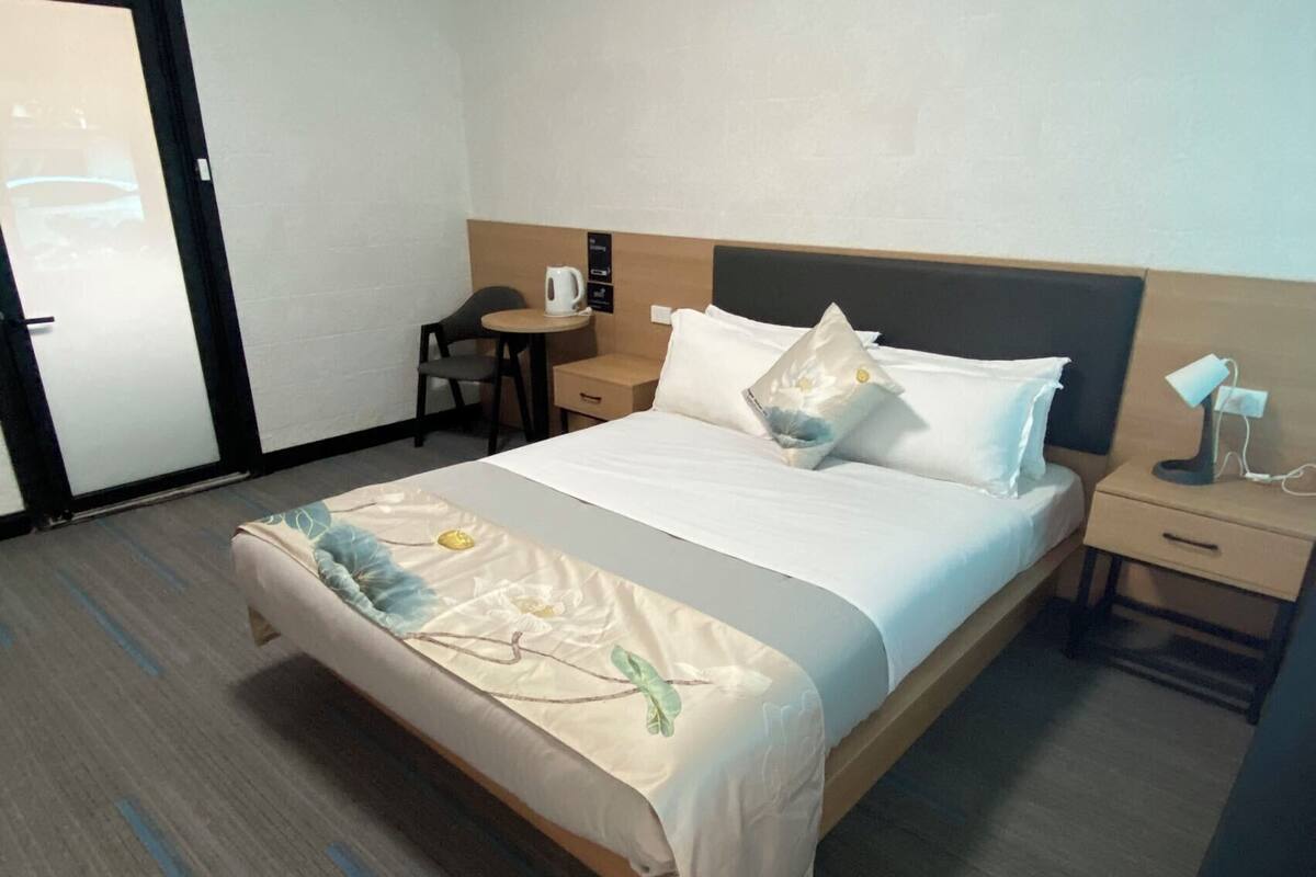 A hotel room with a bed, a desk, a chair, and a small table.