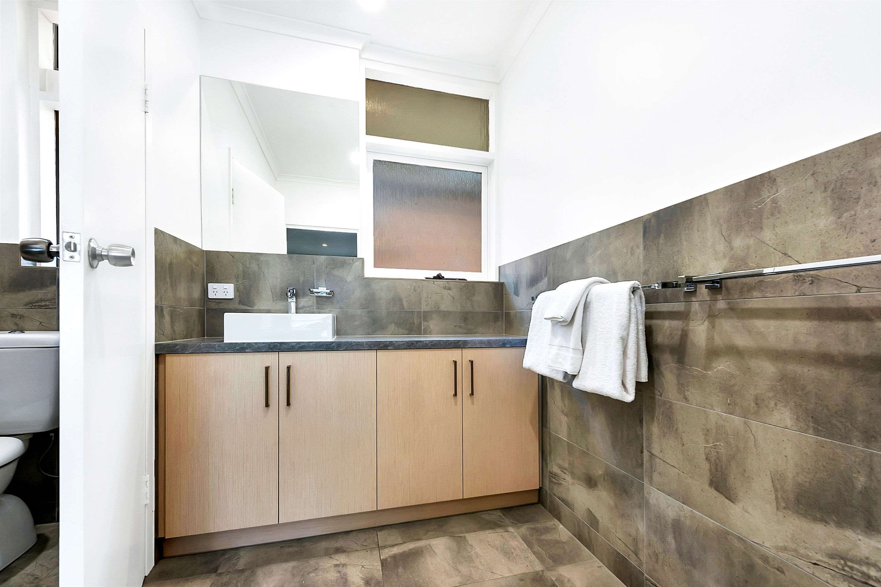 Une salle de bain moderne avec un lavabo, un miroir et un porte-serviettes.