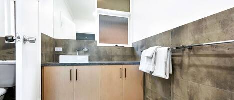 Une salle de bain moderne avec un lavabo, un miroir et un porte-serviettes.