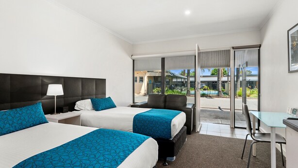 A hotel room with two beds, a desk, and a chair. There is a view of the outside through large windows. - Comfort Inn & Suites Manhattan (Enfield)