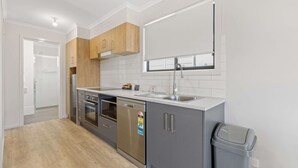A modern kitchen with grey cabinets, a stainless steel dishwasher, and a built-in oven. - Comfort Inn & Suites Manhattan (Enfield)