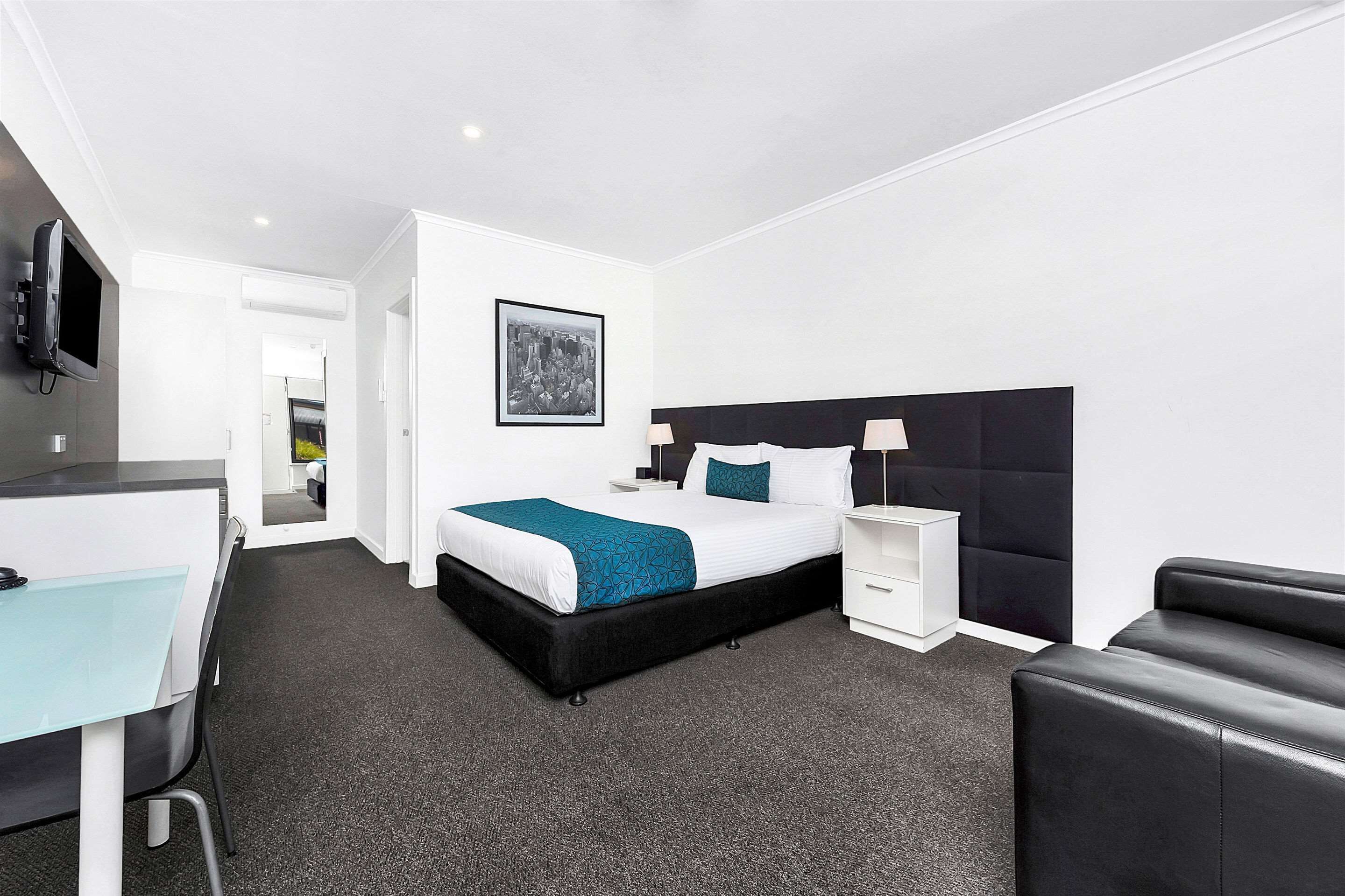 A hotel room with a bed, bedside tables, a desk, and a TV.